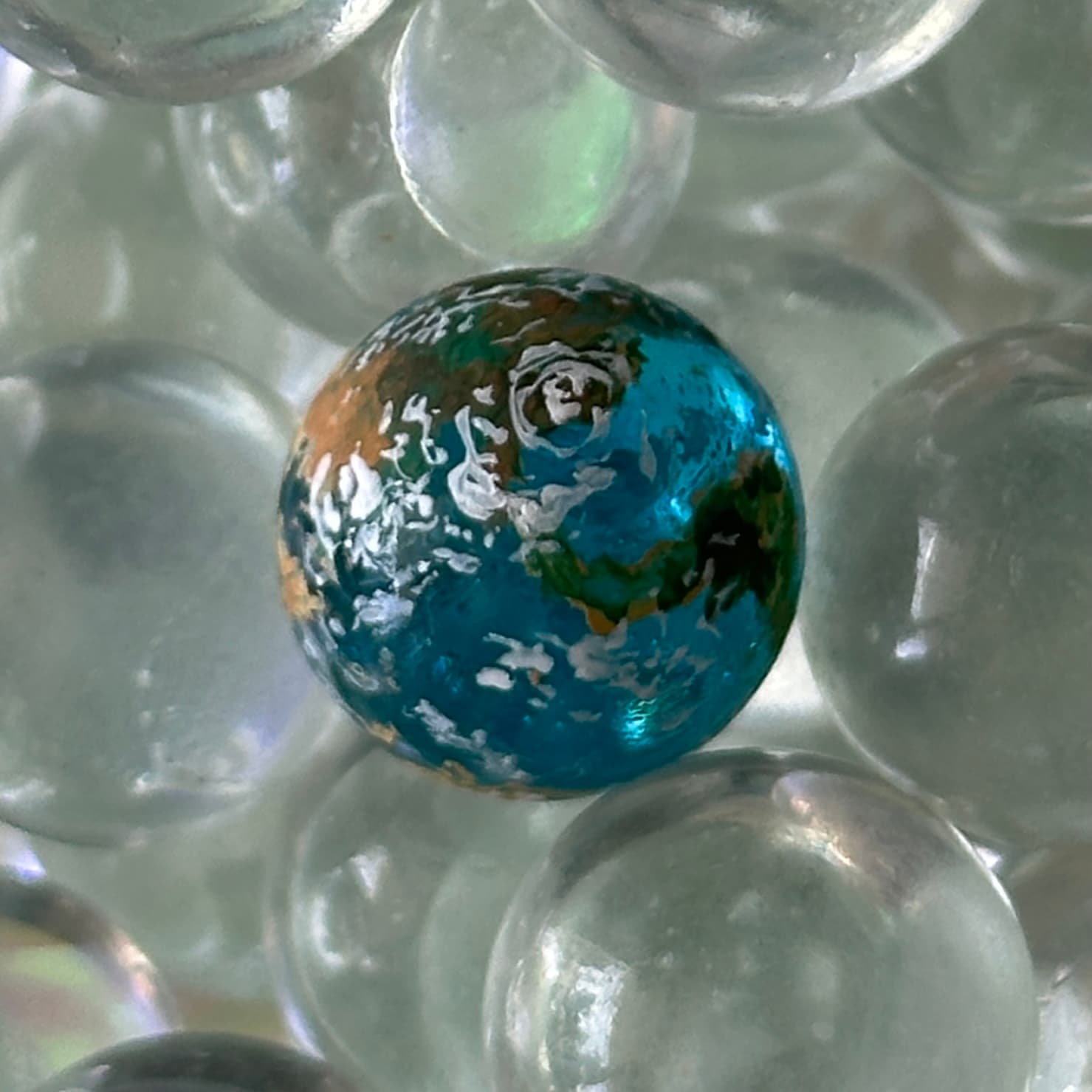 Singular Blue — a single blue Earth among clear glass marbles